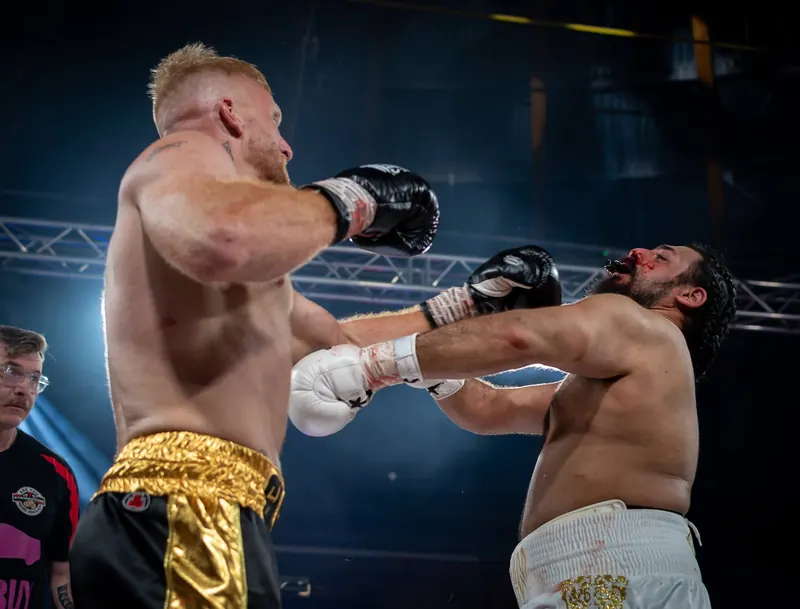 Boxer landing a punch mid-fight under ring lights