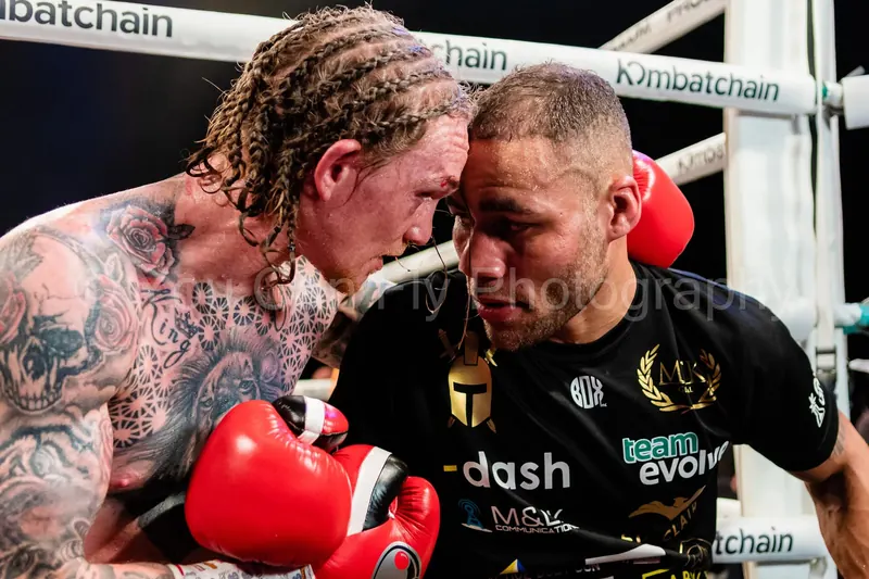 Two boxers head to head in the ring, foreheads touching