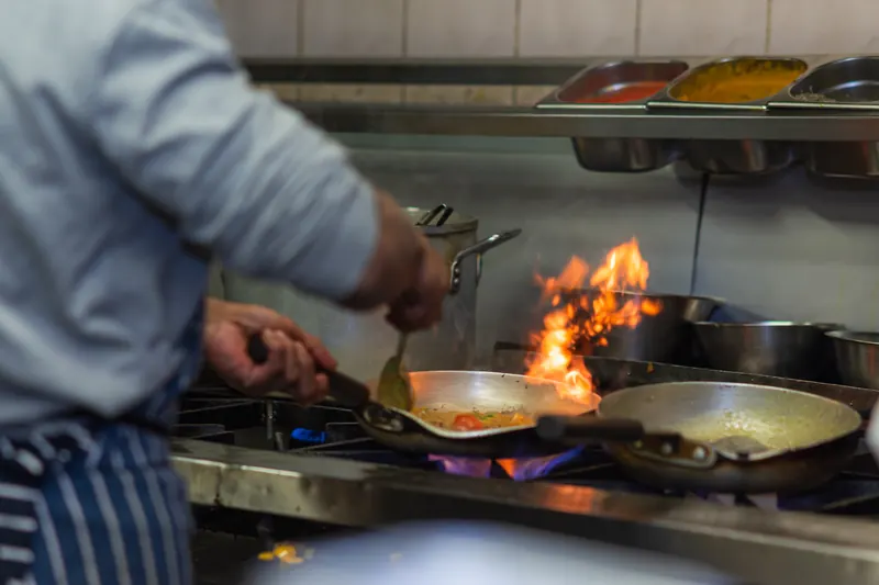 Chef cooking over leaping flames in the kitchen at Concord Tandoori, Washington