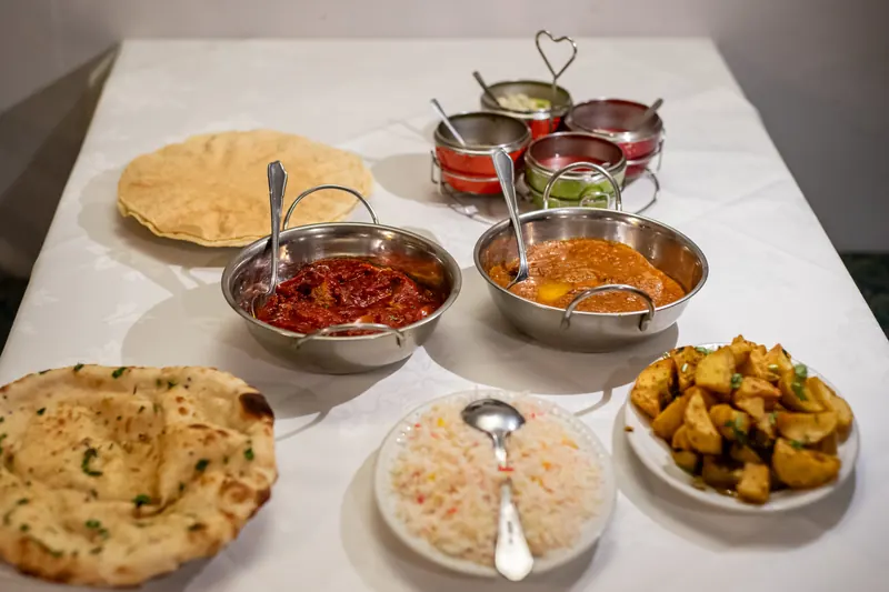 A full spread of curries, rice, naan and sides on a white tablecloth at Concord Tandoori