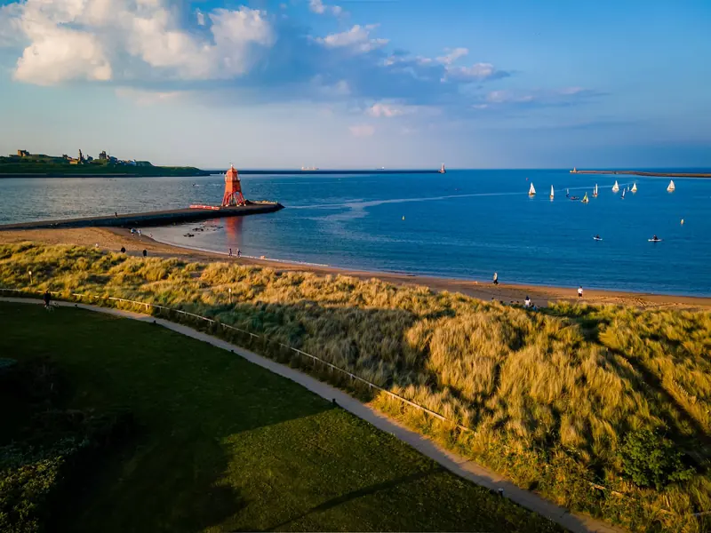 Low drone shot over the dunes towards the Herd Groyne and the mouth of the Tyne