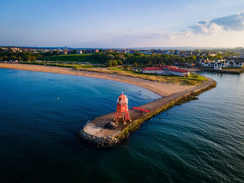 Drone photograph of the red Herd Groyne lighthouse and South Shields beach