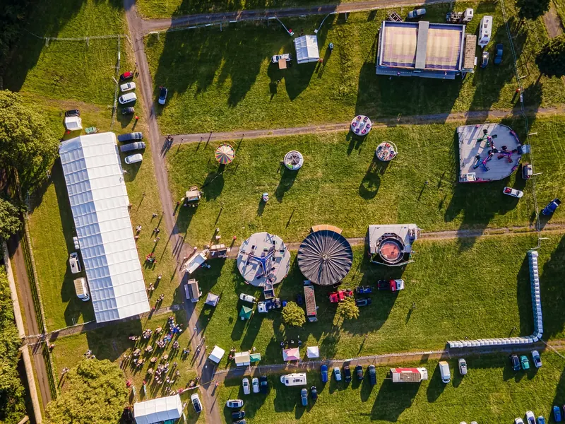 Drone photograph of an outdoor event with marquees, stalls and crowds from above