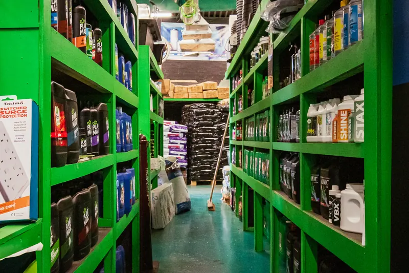 A narrow aisle between bright green shelves packed with hydroponics nutrients and supplies