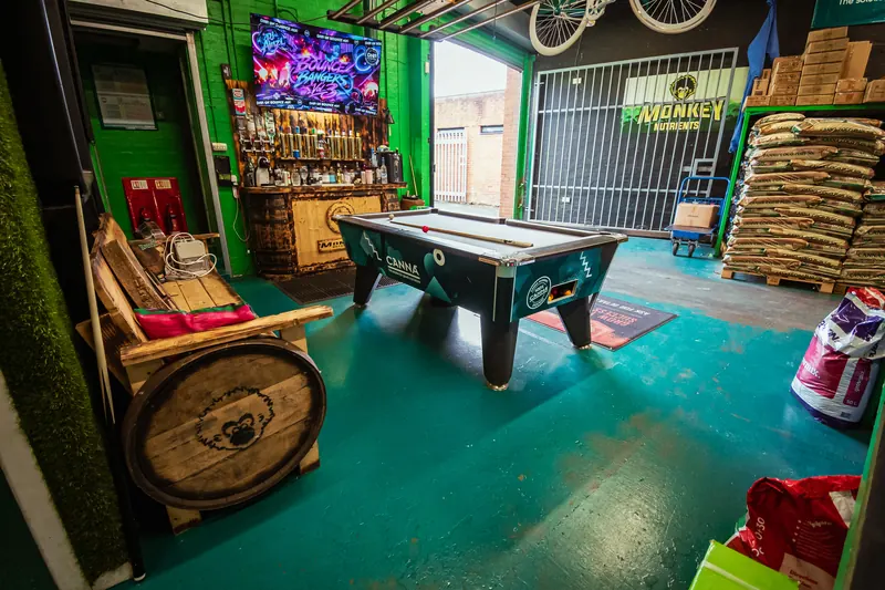Customer lounge area inside Hydro Pro Washington with a pool table, barrel seating and a neon sign