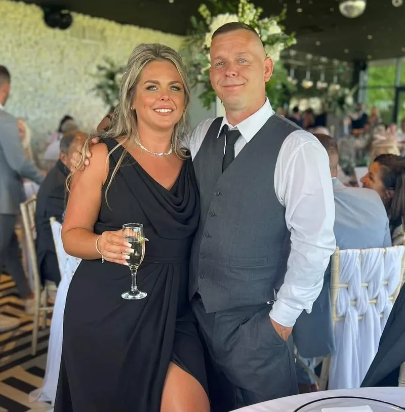 Karn and Laura standing together at a wedding reception, Laura holding a glass of fizz