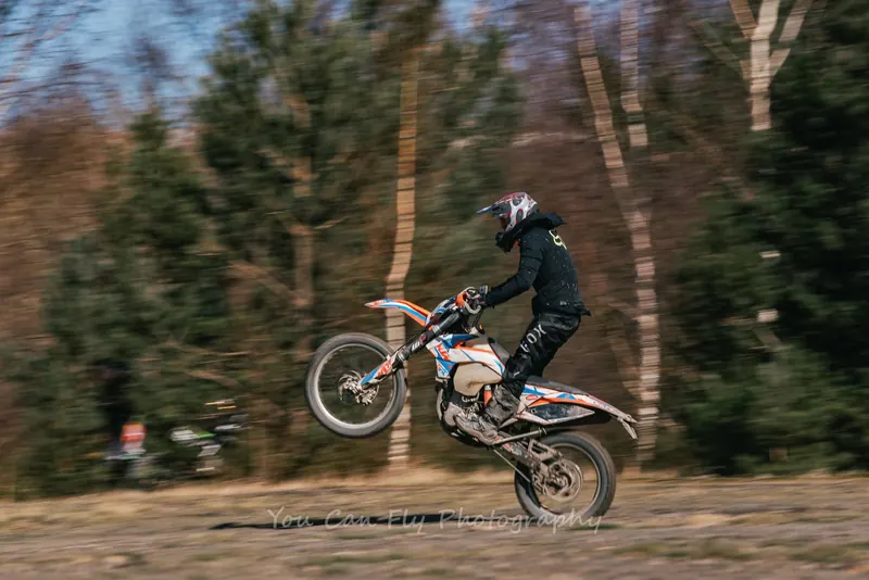 Motocross rider pulling a wheelie through woodland in the North East