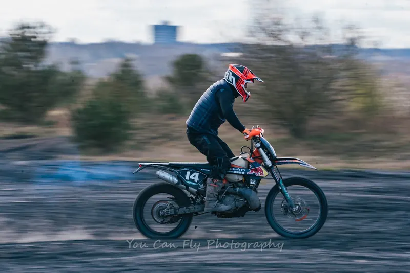 Motocross rider racing across a muddy North East track