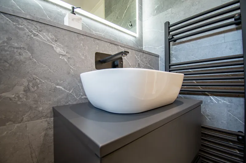 Countertop basin on a dark vanity unit with a black towel rail and grey marble-effect tiles, fitted by Washington Bathroom Solutions