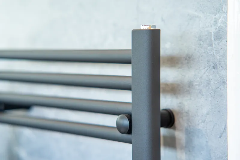 Close-up of a black heated towel rail against marble-effect tiles