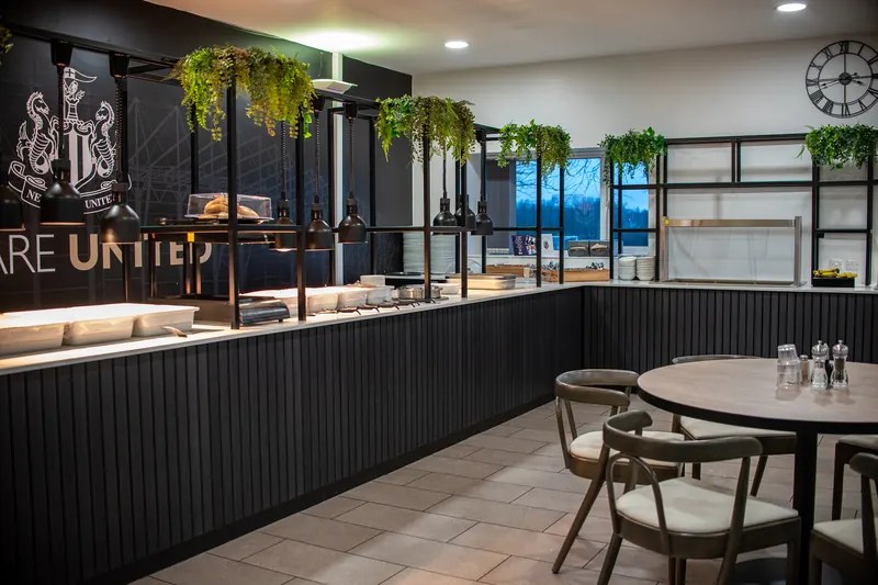 Canteen at Newcastle United’s training ground with a long dark counter and seating, fitted by Washington Worktops