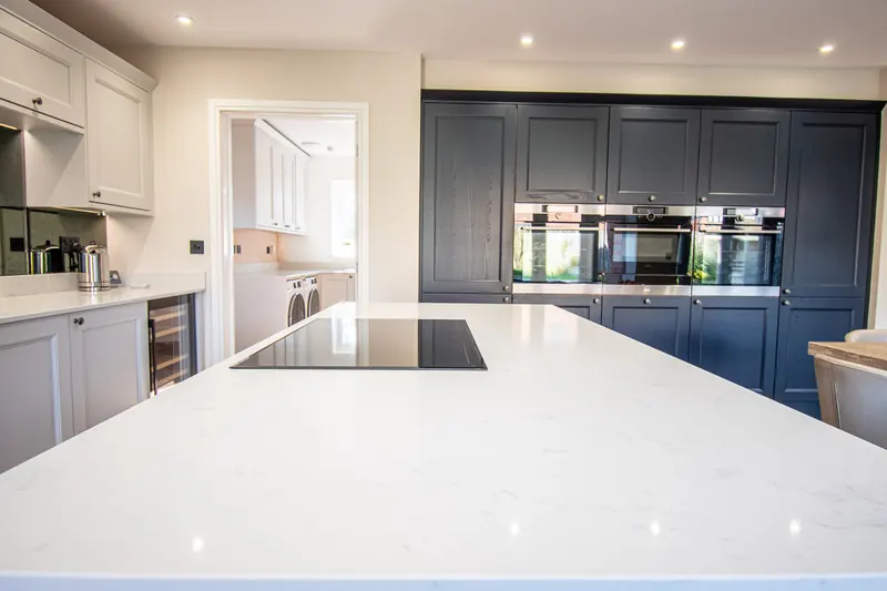 White quartz kitchen island with an induction hob in a navy and white kitchen