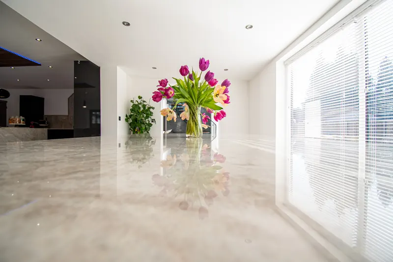 Close view along a polished stone worktop with pink tulips and a window behind